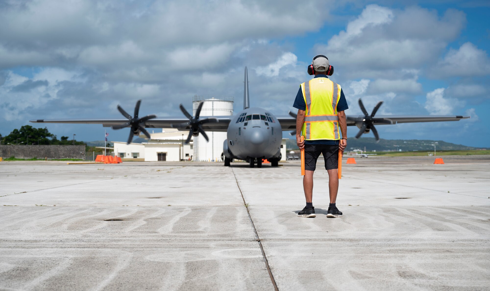An Antonio B. Won Pat International Airport, Guam, civilian prepares to marshal out a C-130J Super Hercules assigned to Dyess Air Force Base, Texas, for a cargo transportation mission during exercise Valiant Shield 24, June 7, 2024. Airmen from the 317th Airlift Wing completed the Agile Combat Employment movement to Andersen Air Force Base, Guam, and Tinian International Airport, Tinian Island, in support of U.S., allied and partner forces developing regional and global power projection capabilities during VS24. (U.S. Air Force photo by Airman 1st Class Emma Anderson)