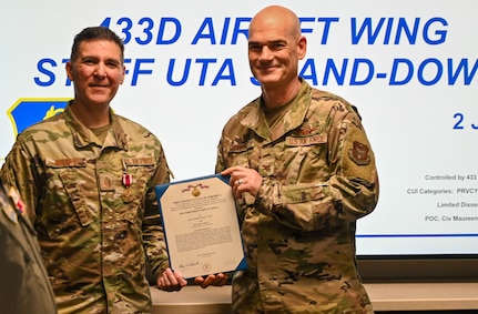 Col. William Gutermuth, 433rd Airlift Wing commander, presents the Meritorious Service Medal decoration to Master Sgt. Gabriel Maciaz, 433rd Command Post senior enlisted leader, during a 433rd AW Staff Unit Training Assembly stand-down meeting on Joint Base San Antonio-Lackland, Texas, June 7, 2024.