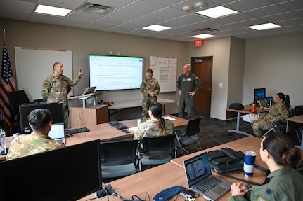 Master Sgt. William Bonner, center left, 433rd Airlift Wing Inspector General of Inspections and self-assessment program manager senior enlisted leader, briefs the accomplishments of Senior Master Sgt. Lisa Anderson, center, 26th Aerial Port Squadron SAPM, for her contribution to the IGI team to Col. William Gutermuth, center right, 433rd AW commander.
