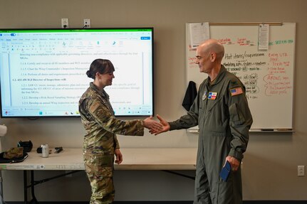 Col. William Gutermuth, 433rd Airlift Wing commander, presents his wing commander’s coin to Senior Master Sgt. Lisa Anderson, 26th Aerial Port Squadron self-assessment program manager, for her support to the Inspector General of Inspections team.