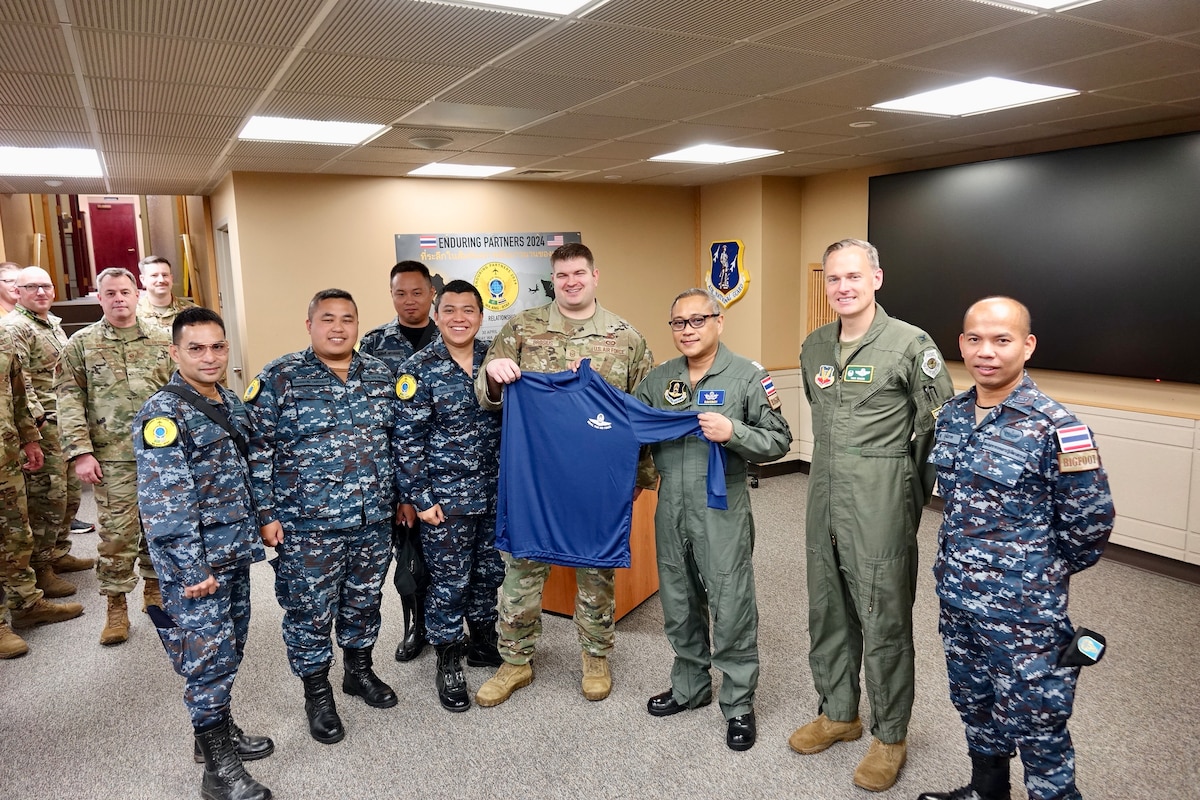 Royal Thai Air Force Gp. Capt. Piriyathrone Suwanruji presents Col. Antony Braun, 225th Air Defense Group commander, and Master Sgt. Matthew Brosius, 225th Air Defense Squadron NCOIC Plans & Operations, with a memento to commemorate Enduring Partners 2024 at the Western Air Defense Sector, Joint Base Lewis-McChord, Washington, May 3, 2024. EP24 is an engagement to improve readiness and combined and joint interoperability between the RTAF and WAANG.