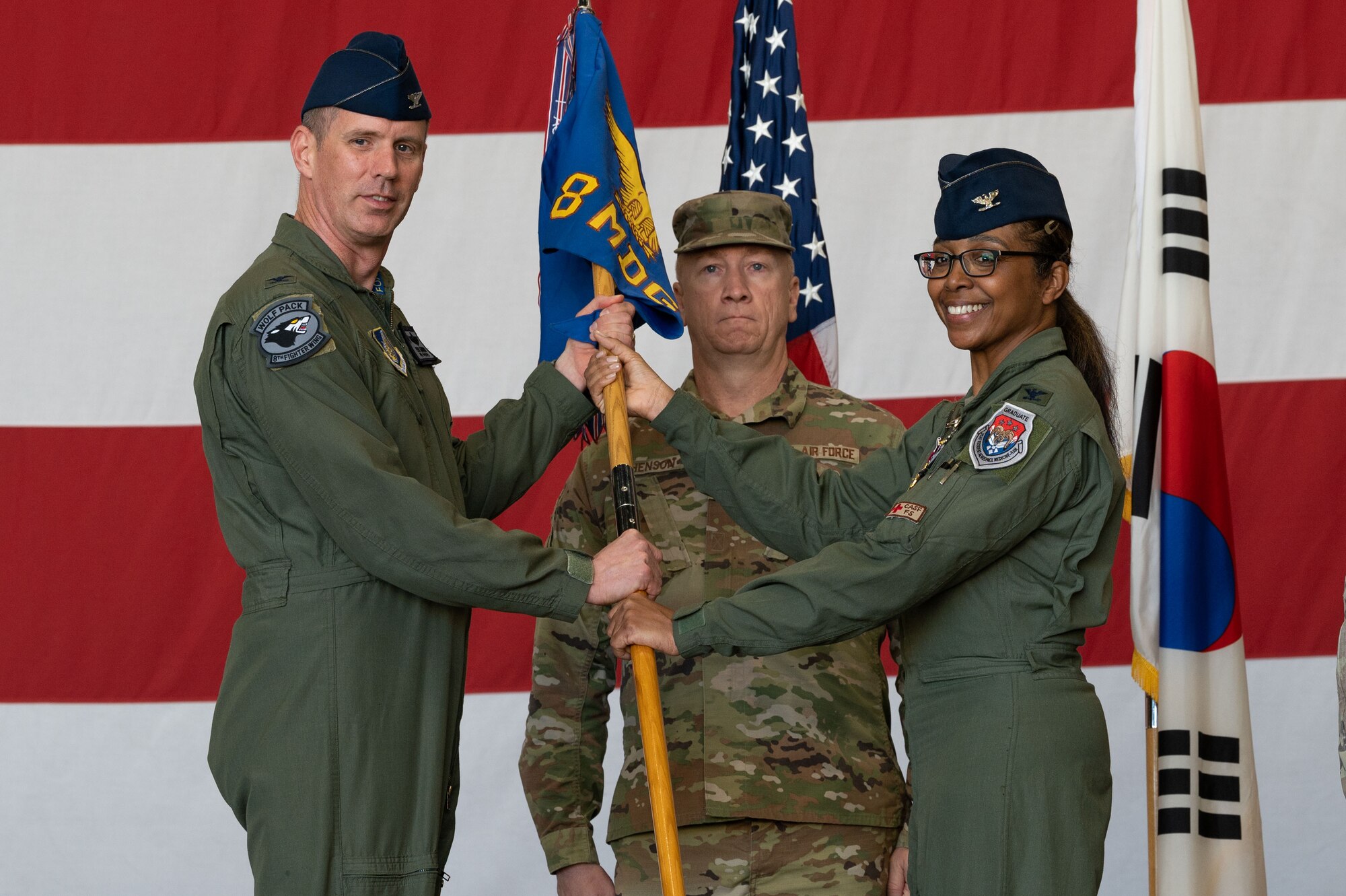 U.S. Air Force Col. Elizabeth Anderson-Doze, 8th Medical Group outgoing commander, passes the guidon to Col. Peter Kasarskis, 8th Fighter Wing commander, during the 8th MDG change of command ceremony.