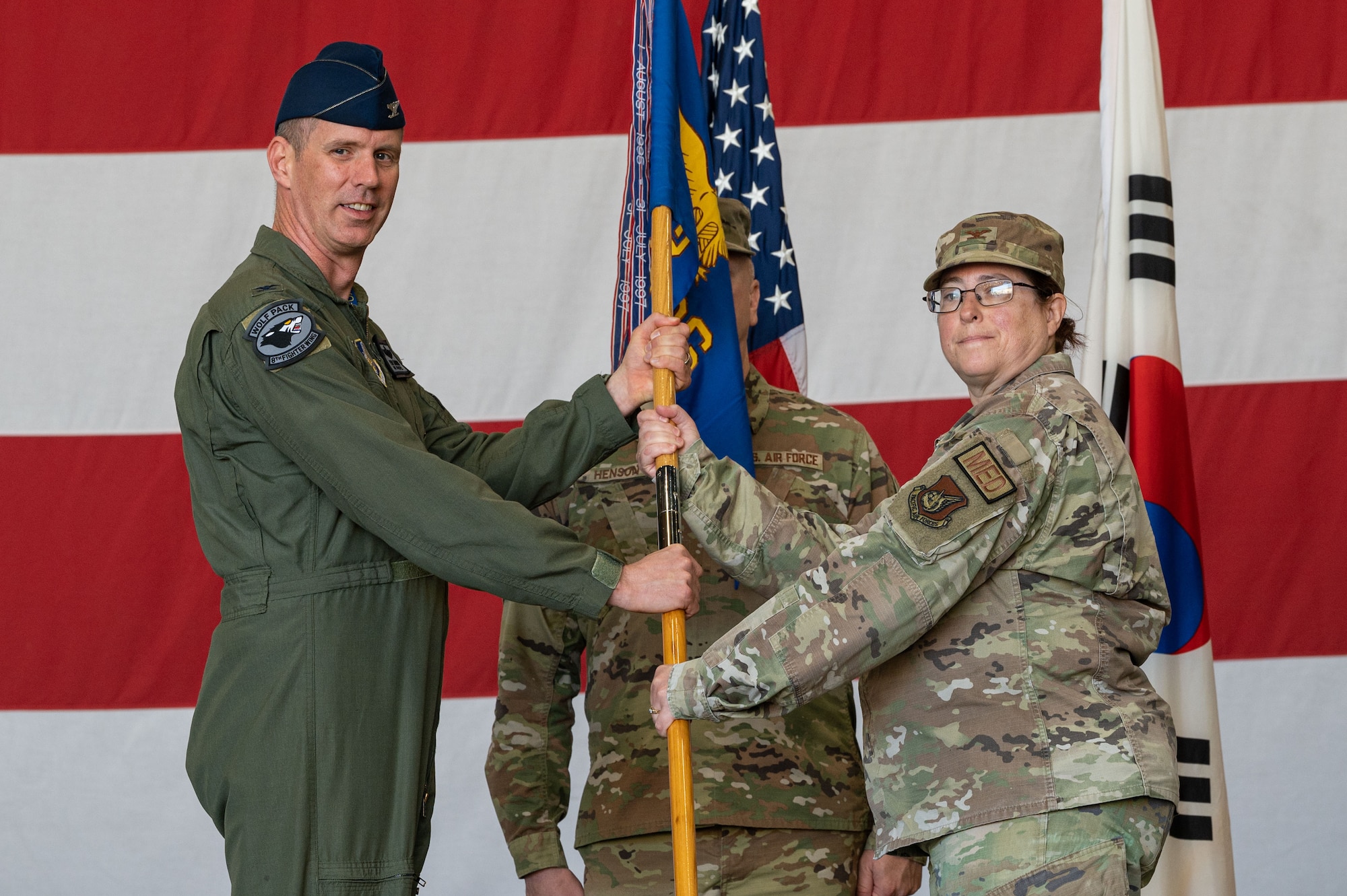 U.S. Air Force Col. Peter Kasarskis, 8th Fighter Wing commander, presents the 8th Medical Group guidon to Col. Valerie OBrien, 8th MDG incoming commander, during the 8th MDG change of command ceremony.