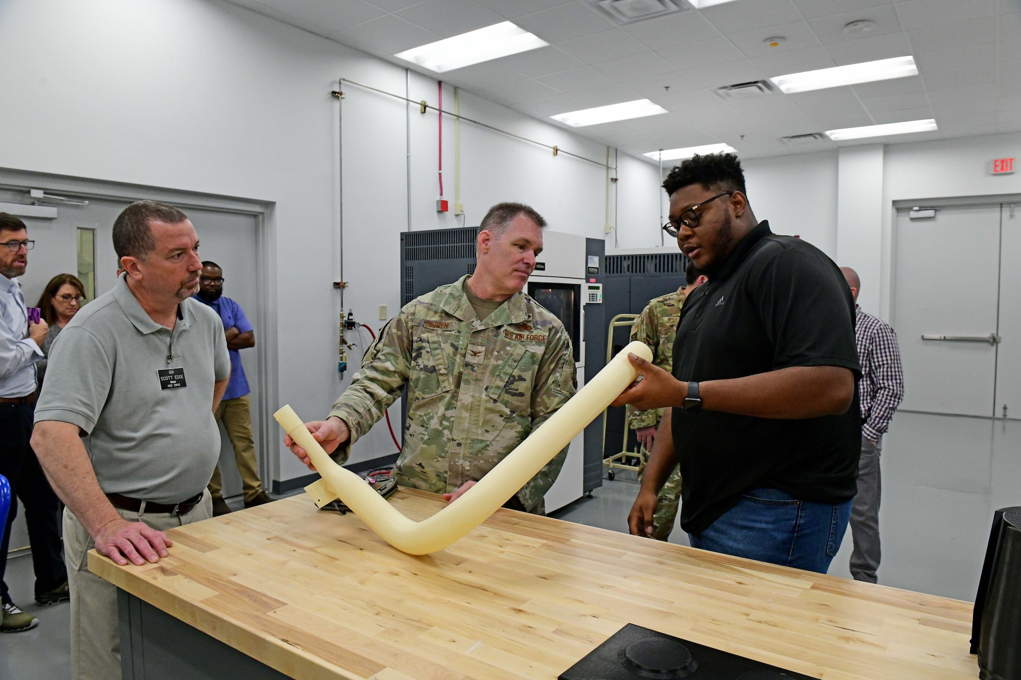 Three men in photo assessing an aircraft part.