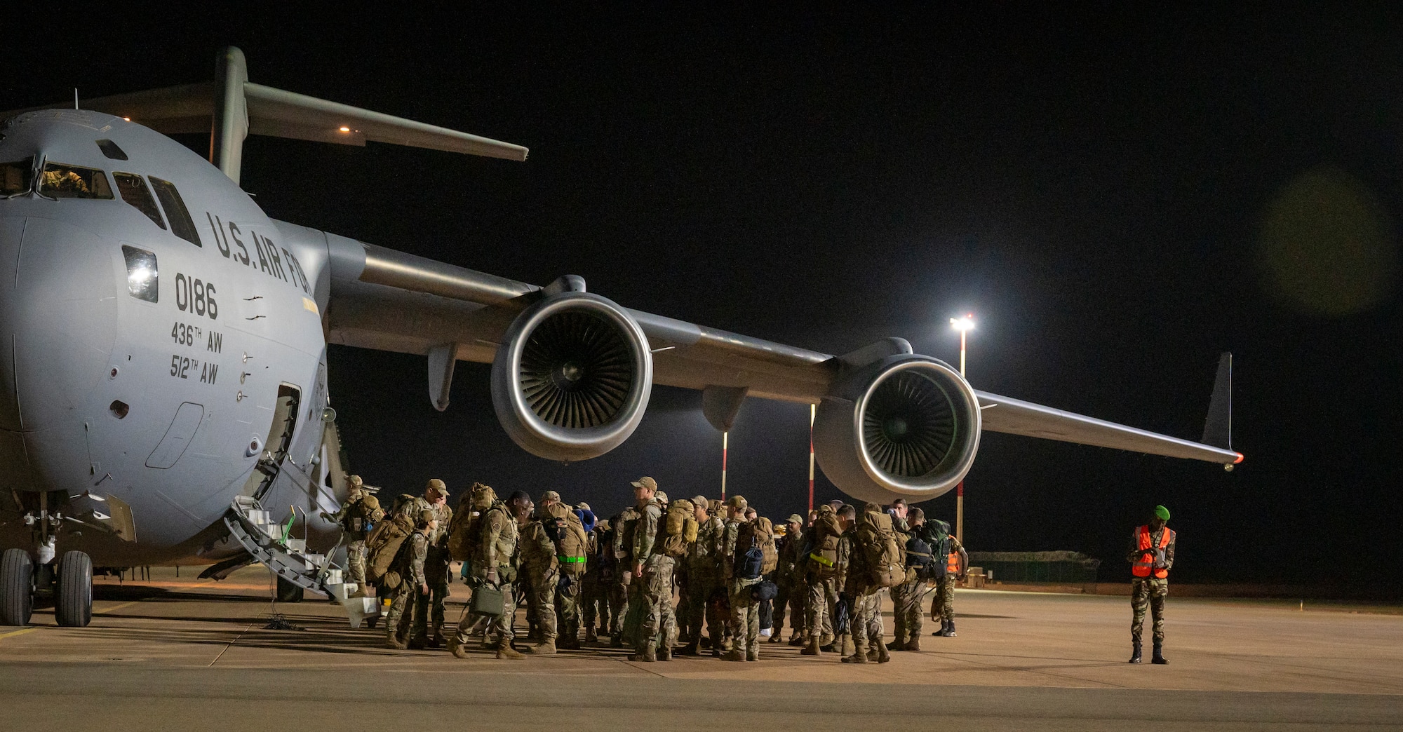 U.S. servicemembers board a C-17 aircraft at night
