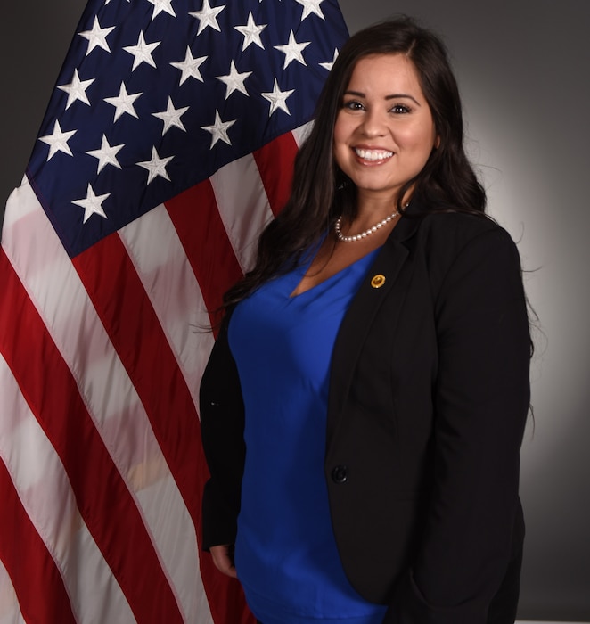 Woman poses for an official studio photo with the American flag in the background.