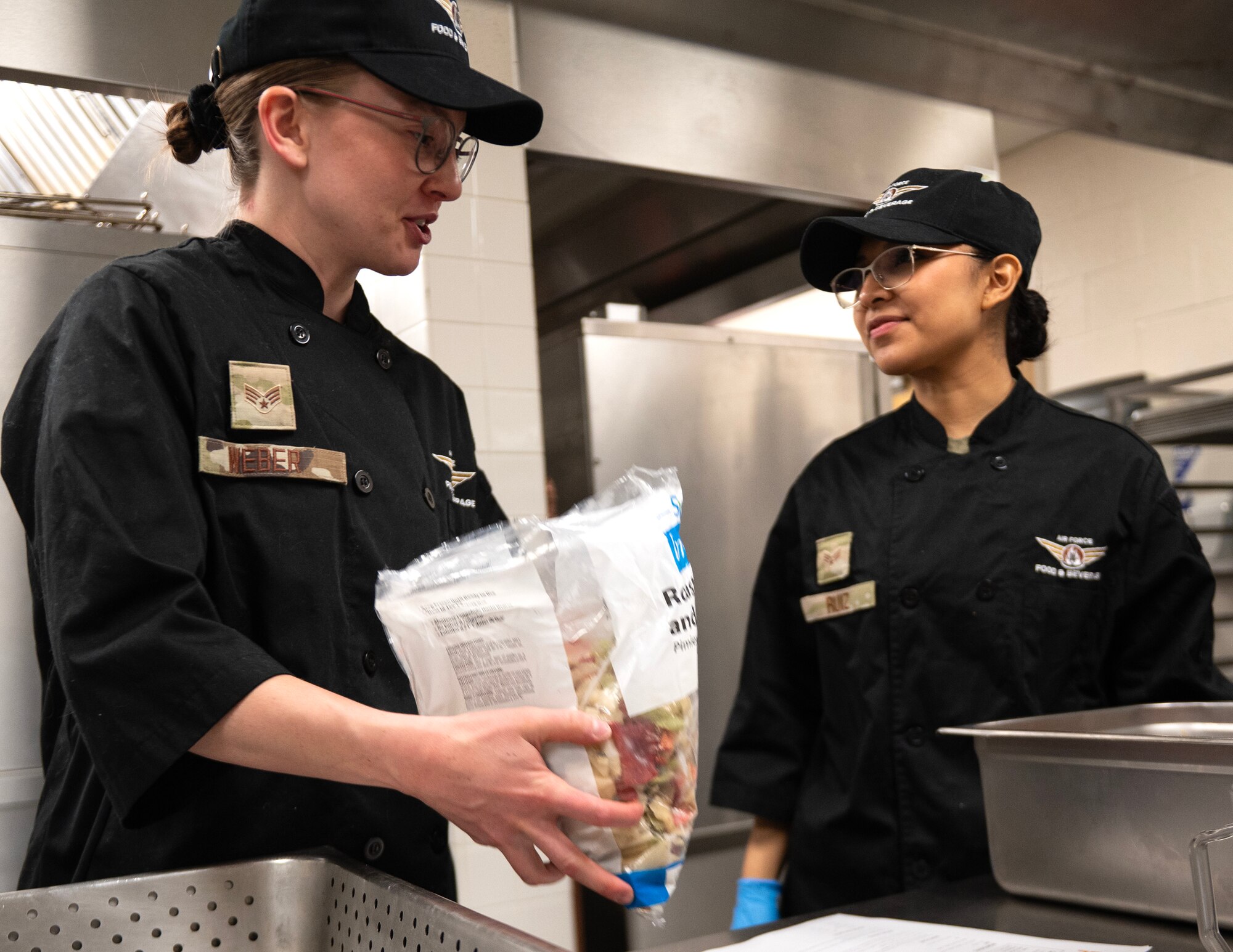 U.S. Air Force Senior Airman Ella Weber, left, and Senior Airman Corina Ruiz, right, prepare food in St. Paul, Minn., May 5, 2024.