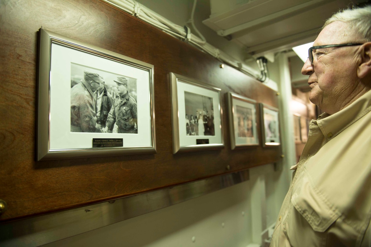 A man looks at an old photo of two men shaking hands.