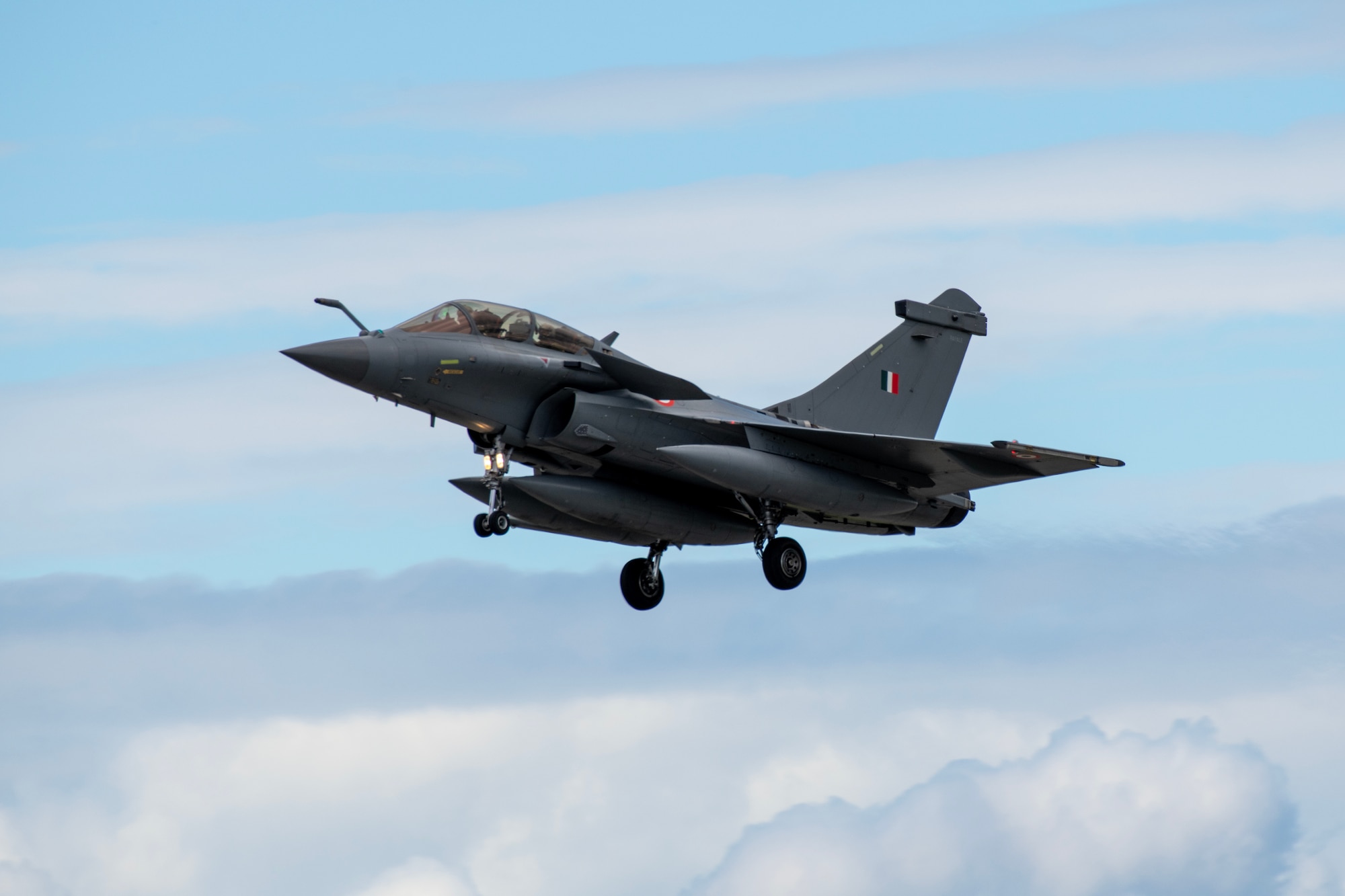 An Indian Air Force Rafale aircraft flies through the clouds.