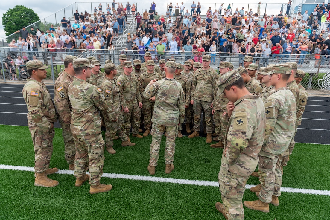 Soldiers with Company A, 1st Battalion, 178th Infantry Regiment, Illinois Army National Guard, huddle around Sgt. 1st Class Paul Minder, platoon sergeant, Company A, before a mobilization ceremony in Peoria, Illinois, June 4, 2024.