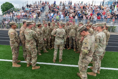 Soldiers with Company A, 1st Battalion, 178th Infantry Regiment, Illinois Army National Guard, huddle around Sgt. 1st Class Paul Minder, platoon sergeant, Company A, before a mobilization ceremony in Peoria, Illinois, June 4, 2024.