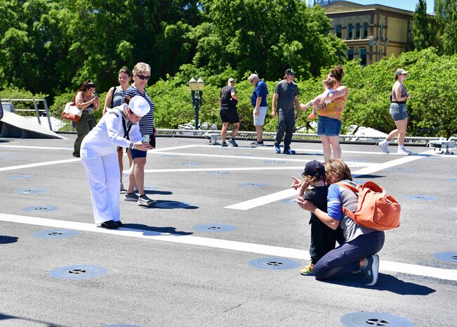 Damage Controlman 2nd Class Chloe Hill, assigned to the Independence-variant littoral combat ship USS Montgomery (LCS 8), takes a photo of ship tour guests during Portland Fleet Week in Portland, Oregon June 6, 2024. Portland Fleet Week is a time-honored celebration of the sea services and provides an opportunity for the citizens of Oregon to meet Sailors, Marines and Coast Guardsmen, as well as witness firsthand the latest capabilities of today’s maritime services. (U.S. Navy photo by Mass Communication Specialist 1st Class Heather C. Wamsley)