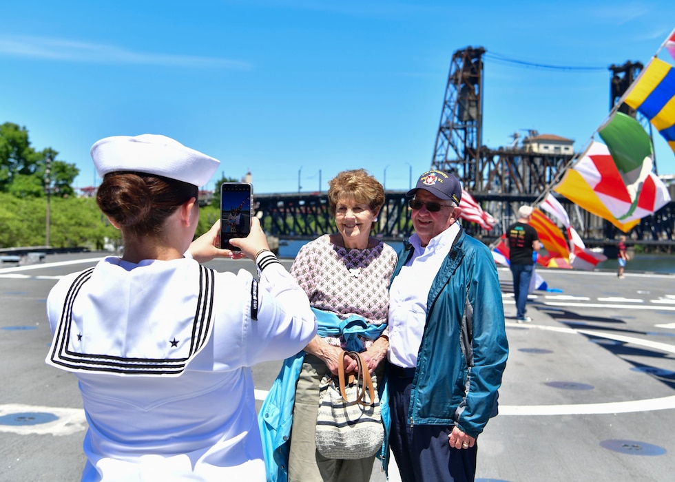 Damage Controlman 2nd Class Chloe Hill, assigned to the Independence-variant littoral combat ship USS Montgomery (LCS 8), takes a photo of ship tour guests Gene and Mary Ferrell, from Omaha, Nebraska, during Portland Fleet Week in Portland, Oregon June 6, 2024. Portland Fleet Week is a time-honored celebration of the sea services and provides an opportunity for the citizens of Oregon to meet Sailors, Marines and Coast Guardsmen, as well as witness firsthand the latest capabilities of today’s maritime services. (U.S. Navy photo by Mass Communication Specialist 1st Class Heather C. Wamsley)