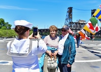 Damage Controlman 2nd Class Chloe Hill, assigned to the Independence-variant littoral combat ship USS Montgomery (LCS 8), takes a photo of ship tour guests Gene and Mary Ferrell, from Omaha, Nebraska, during Portland Fleet Week in Portland, Oregon June 6, 2024. Portland Fleet Week is a time-honored celebration of the sea services and provides an opportunity for the citizens of Oregon to meet Sailors, Marines and Coast Guardsmen, as well as witness firsthand the latest capabilities of today’s maritime services. (U.S. Navy photo by Mass Communication Specialist 1st Class Heather C. Wamsley)