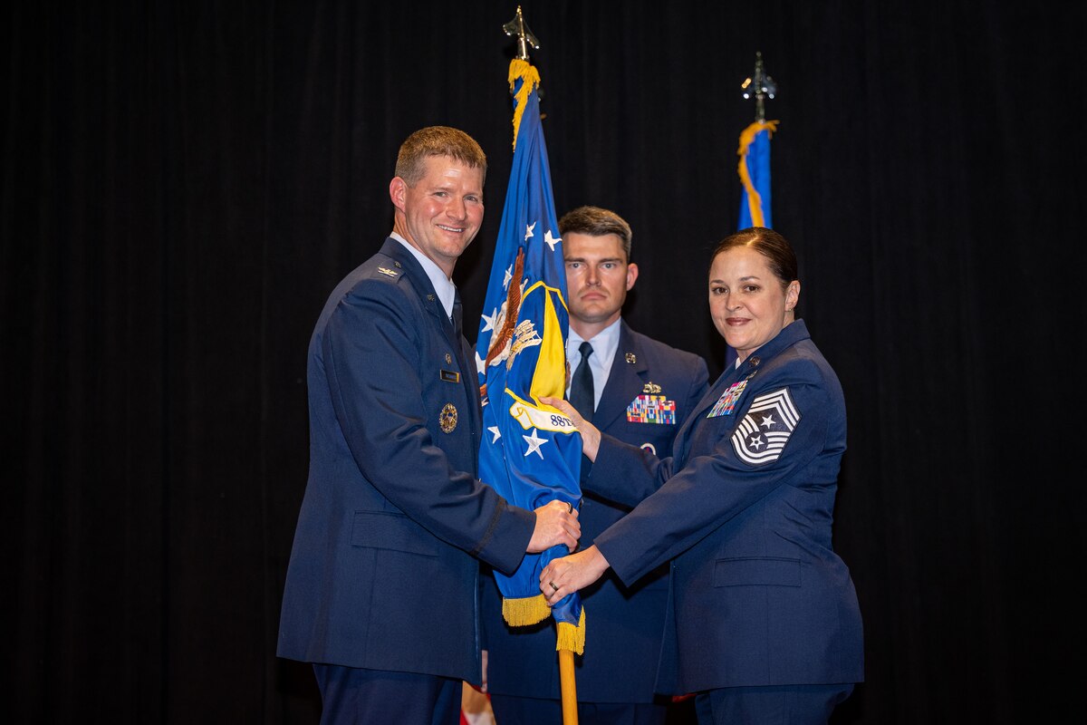Chief Master Sgt. Fontaine poses for a photo as she passes the wing guidon to Col. Richards