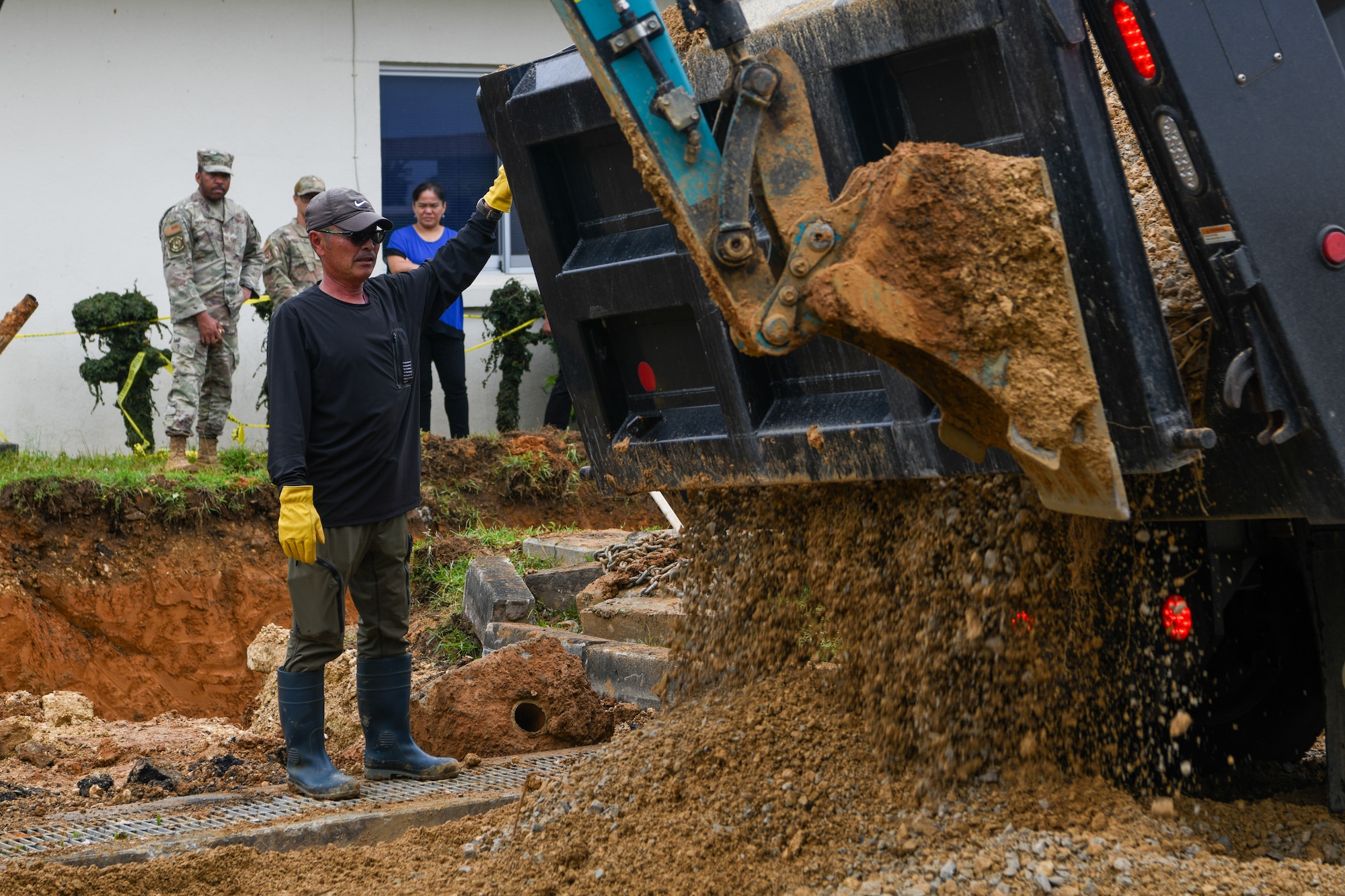 A Master Labor Contractor signals a truck driver unloading sediments when to stop.