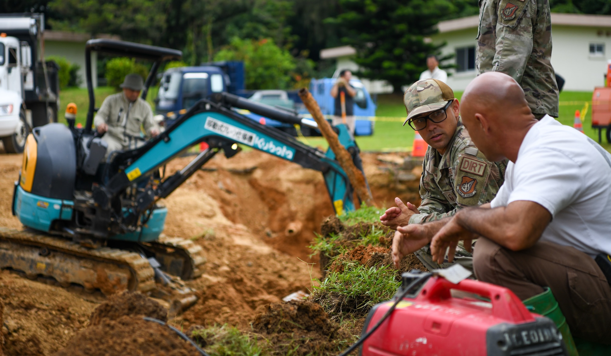 Master labor contractors and U.S. Air Force Airmen discuss and work on an emergency ground repair.