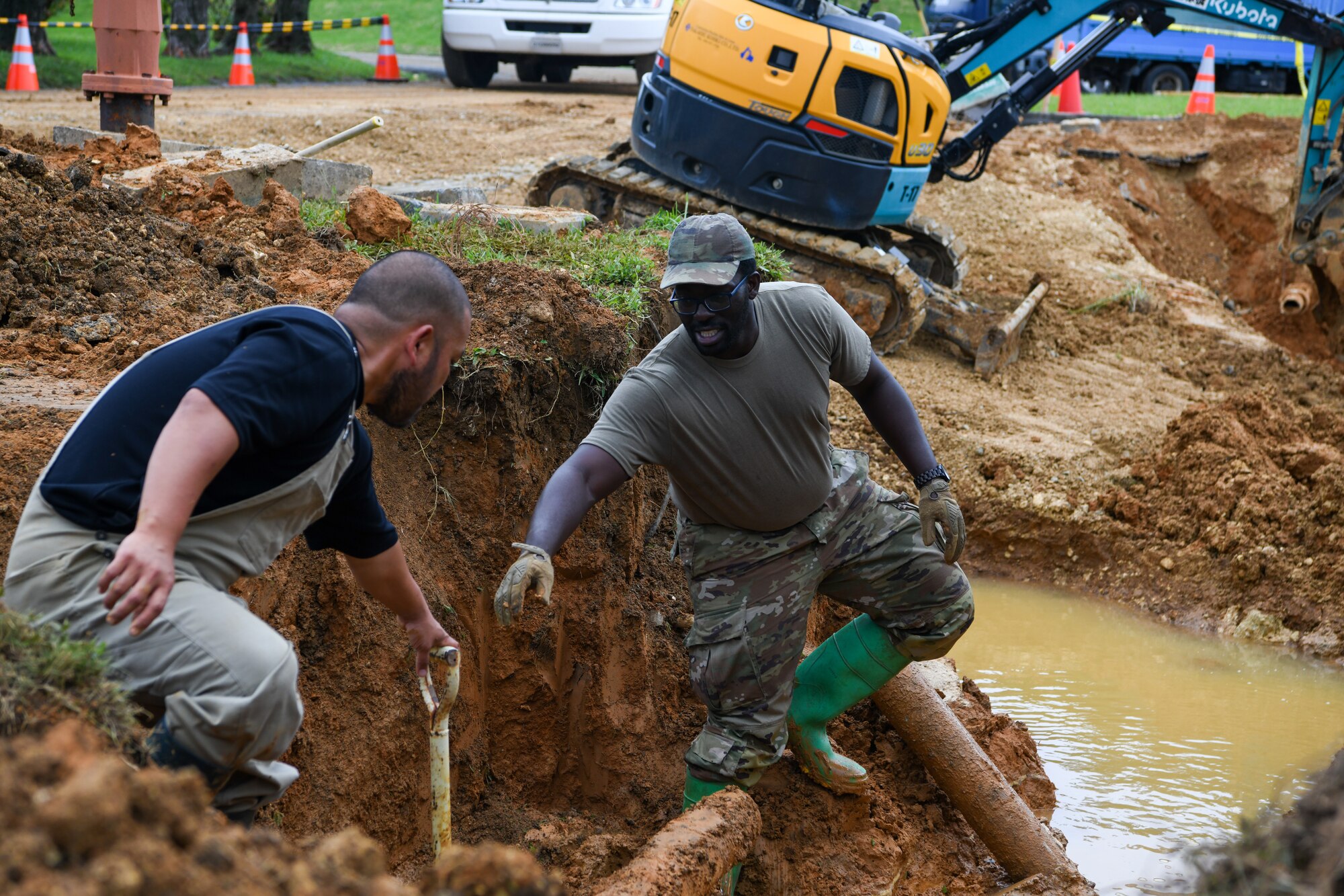 A Japanese Master Labor Contractor passes a shovel to a U.S. Air Force Airman.
