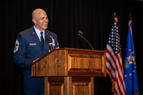 Chief Master Sgt. Morales laughs while standing behind a podium