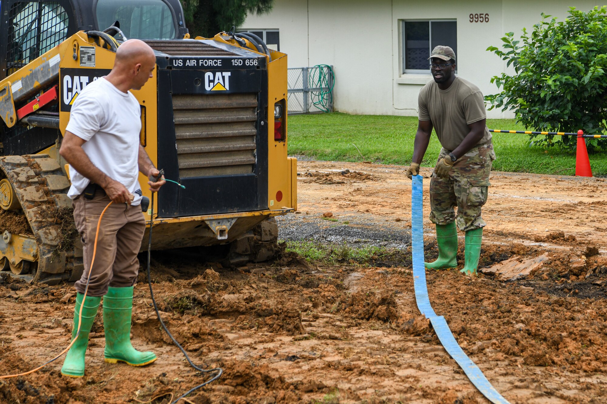 A U.S. Air Force Airmen and Civilian contractor prepare a construction tool for use in an emergency ground repair operation.