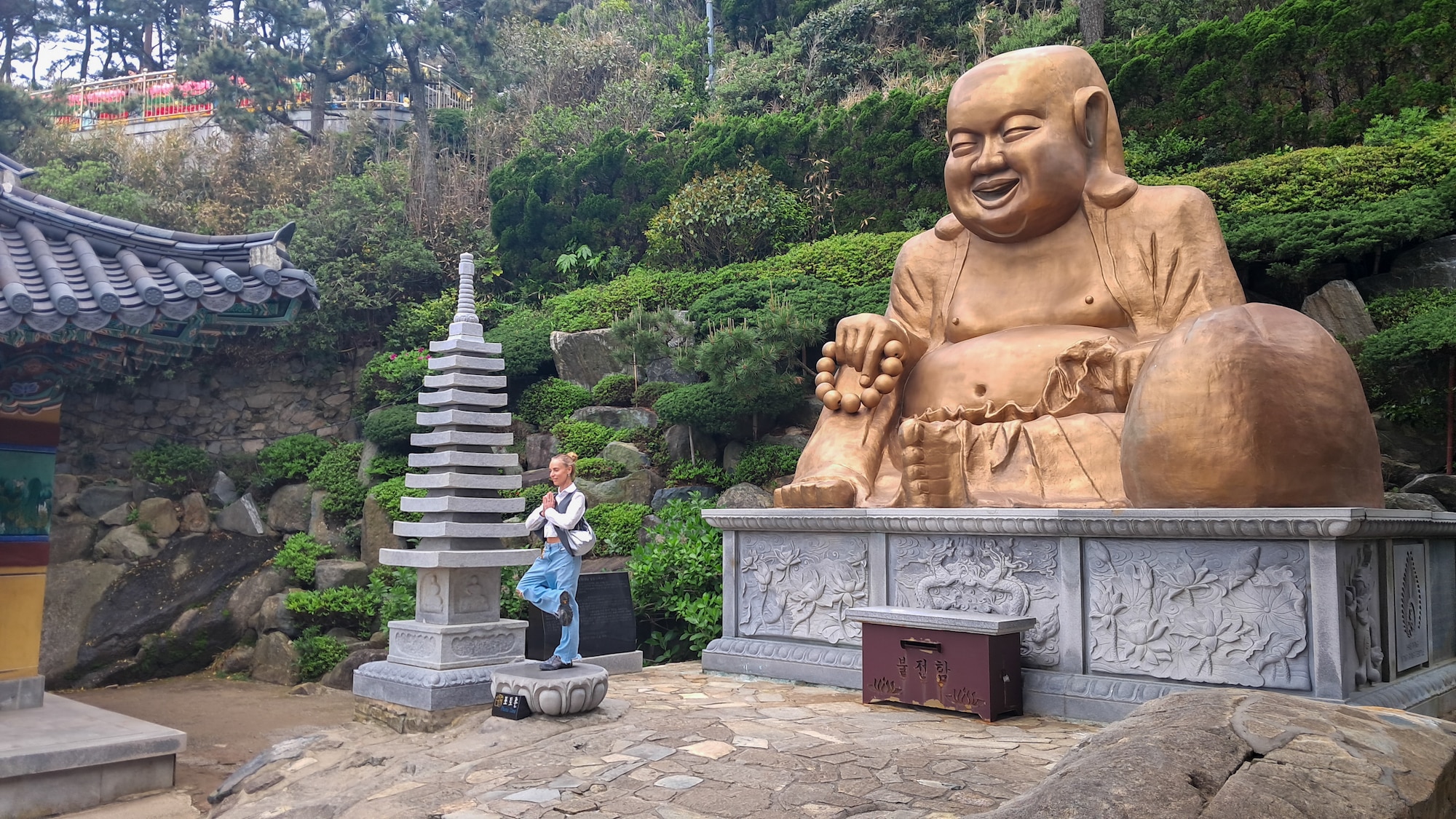 A visitor poses near a Buddha statue at Haedong Yonggungsa Temple, Republic of Korea, May 1, 2024.