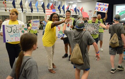 Children high five adults holding welcome home signs