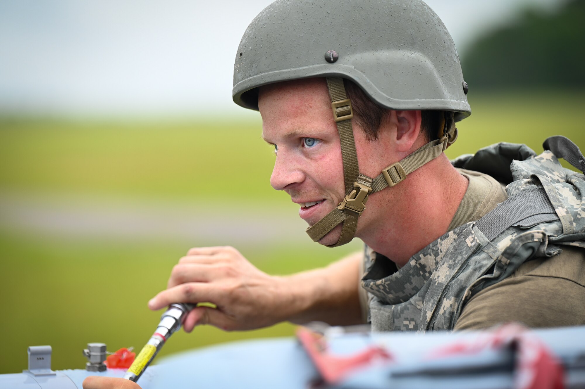 Military member works on bomb outside.