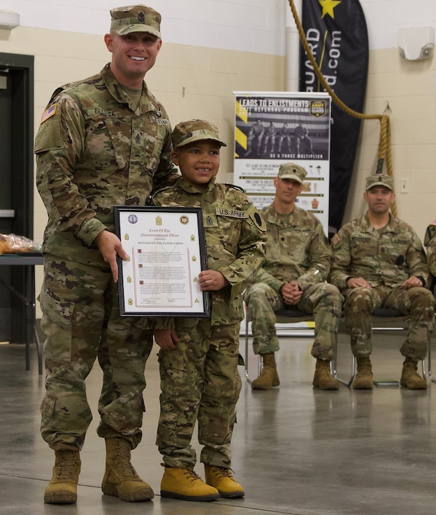 Seven-Year-Old Jamir Gibbs of Marion, Illinois, holds the NCO Creed with 1st Sgt. Beau Detrick of November Company, Recruit Sustainment Program, Illinois Army National Guard Recruiting and Retention Command.
