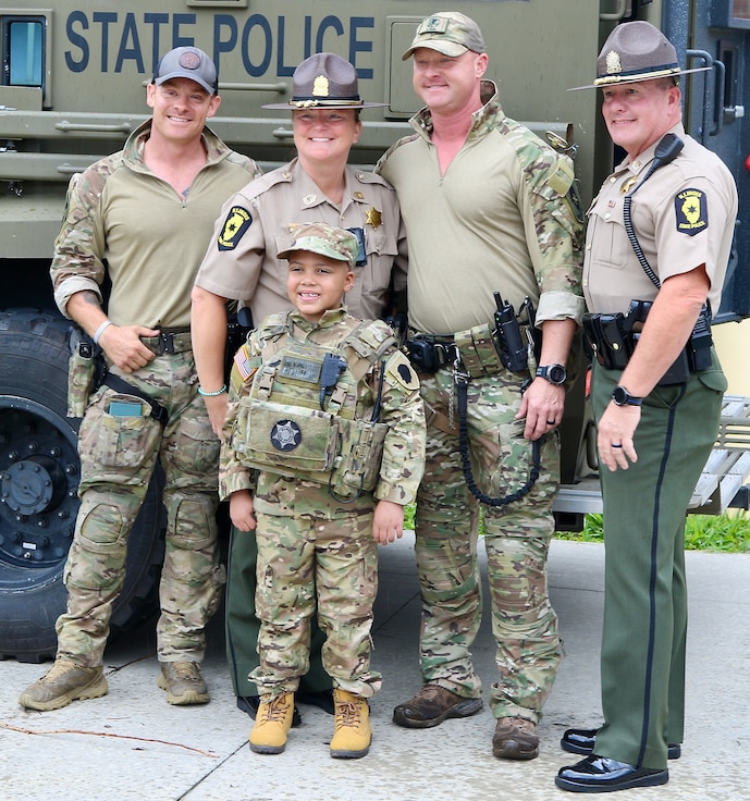 Seven-year-old Jamir Gibbs of Marion, Illinois, smiles as he takes a photo with Illinois State Police officers after his "promotion" ceremony. Jamir was promoted to "Honorary First Sergeant" of the Illinois Army National Guard's November Company, Recruit Sustainment Program, Recruiting and Retention Battalion during a ceremony on June 8 at the Illinois Army National Guard's Marion Readiness Center in honor of his courageous fight against cancer.