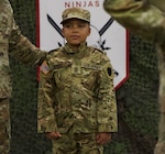 Seven-Year-Old Jamir Gibbs of Marion, Illinois, stands in front of the formation with 1st Sgt. Beau Detrick of November Company, Recruit Sustainment Program, Illinois Army National Guard Recruiting and Retention Command. Jamir was promoted to 