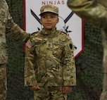 Seven-Year-Old Jamir Gibbs of Marion, Illinois, stands in front of the formation with 1st Sgt. Beau Detrick of November Company, Recruit Sustainment Program, Illinois Army National Guard Recruiting and Retention Command. Jamir was promoted to "Honorary First Sergeant" of November Company during a ceremony on June 8 at the Illinois Army National Guard's Marion Readiness Center in honor of his courageous fight against cancer.