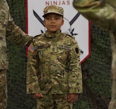 Seven-Year-Old Jamir Gibbs of Marion, Illinois, stands in front of the formation with 1st Sgt. Beau Detrick of November Company, Recruit Sustainment Program, Illinois Army National Guard Recruiting and Retention Command. Jamir was promoted to "Honorary First Sergeant" of November Company during a ceremony on June 8 at the Illinois Army National Guard's Marion Readiness Center in honor of his courageous fight against cancer.