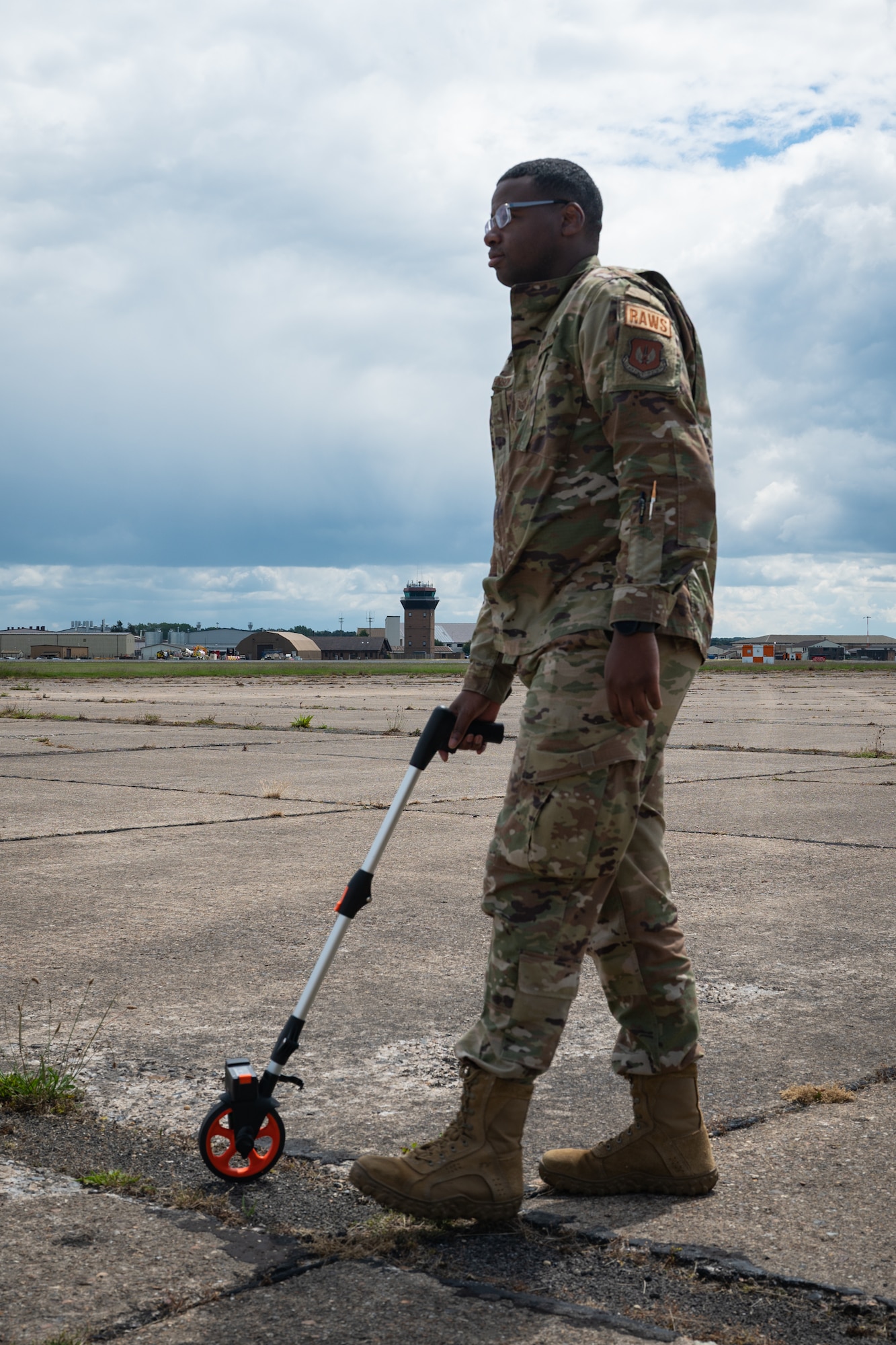 U.S. Air Force member verifies pavement dimensions with measuring wheel.