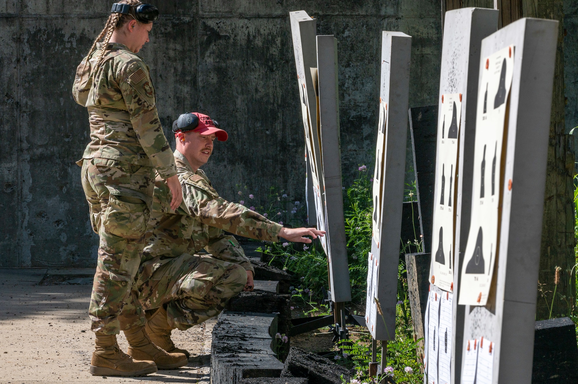 A kneeling man points to a target as a woman stands beside him
