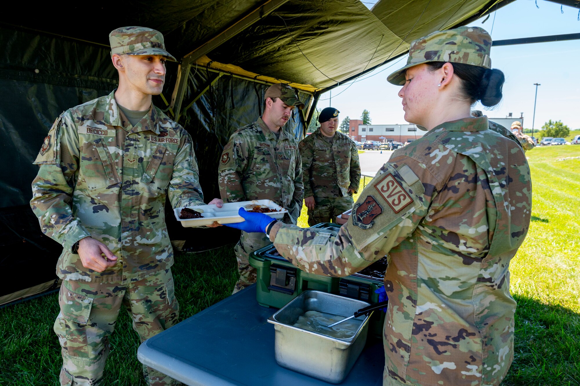 a women hands a tray of food to a man
