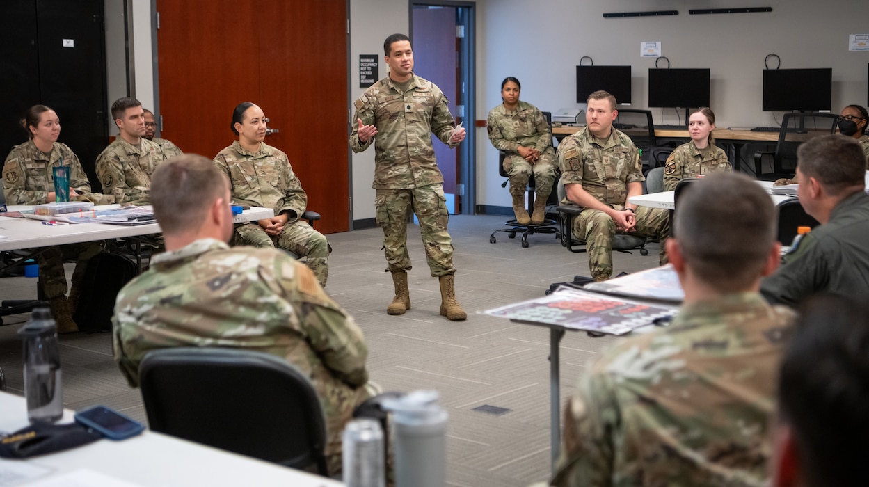 Lt. Col. speaks to leadership what was learned during a Lead Wing Command and Control Course in the middle of his classmates.
