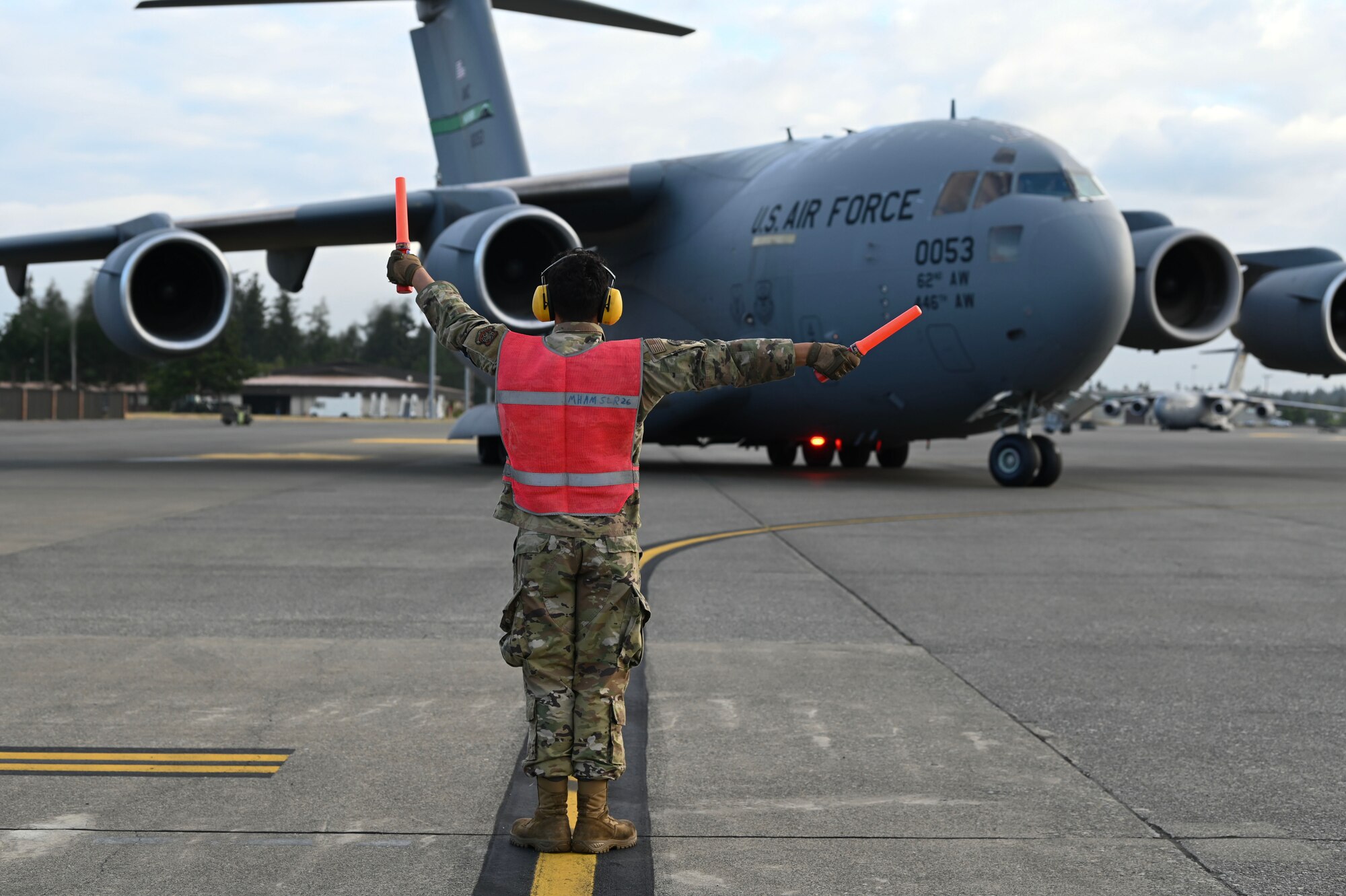 U.S. Air Force Airman 1st Class Josue Escobar, a crew chief with the 62d Aircraft Maintenance Squadron, marshals a C-17 Globemaster III off the flightline at Joint Base Lewis-McChord, Washington, June 12, 2024. Crew chiefs are responsible for aircraft maintenance, including inspections, services and repairs. (U.S. Air Force photo by Airman 1st Class Kylee Tyus)