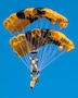 man wearing a parachute jump suit, flying with another person wearing a parachute jump suit, while parachuting.