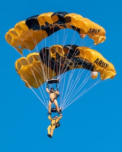 man wearing a parachute jump suit, flying with another person wearing a parachute jump suit, while parachuting.