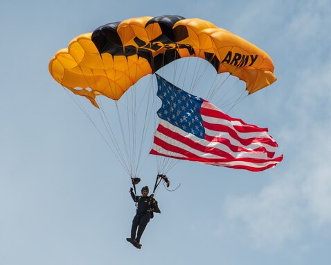 man wearing a parachute jump suit, flying the USA Flag while parachuting.