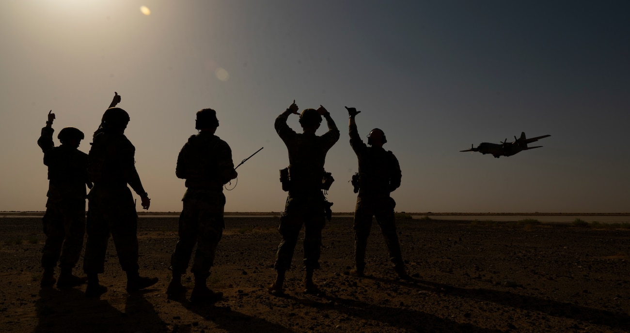 Members of the U.S. Air Force 378th Expeditionary Operation Support Squadron tactical airfield operations cell cheer as a partner C-130 Hercules flies by