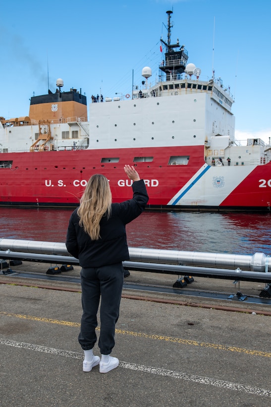 The spouse of a Coast Guard Cutter Healy (WAGB 20) crewmember waves goodbye as the cutter departs Base Seattle for a multi-month Arctic deployment, June 12, 2024. The Healy was commissioned in 2000 and is one of two active polar icebreakers in the Coast Guard's fleet. (U.S. Coast Guard photo by Petty Officer 3rd Class Annika Hirschler)