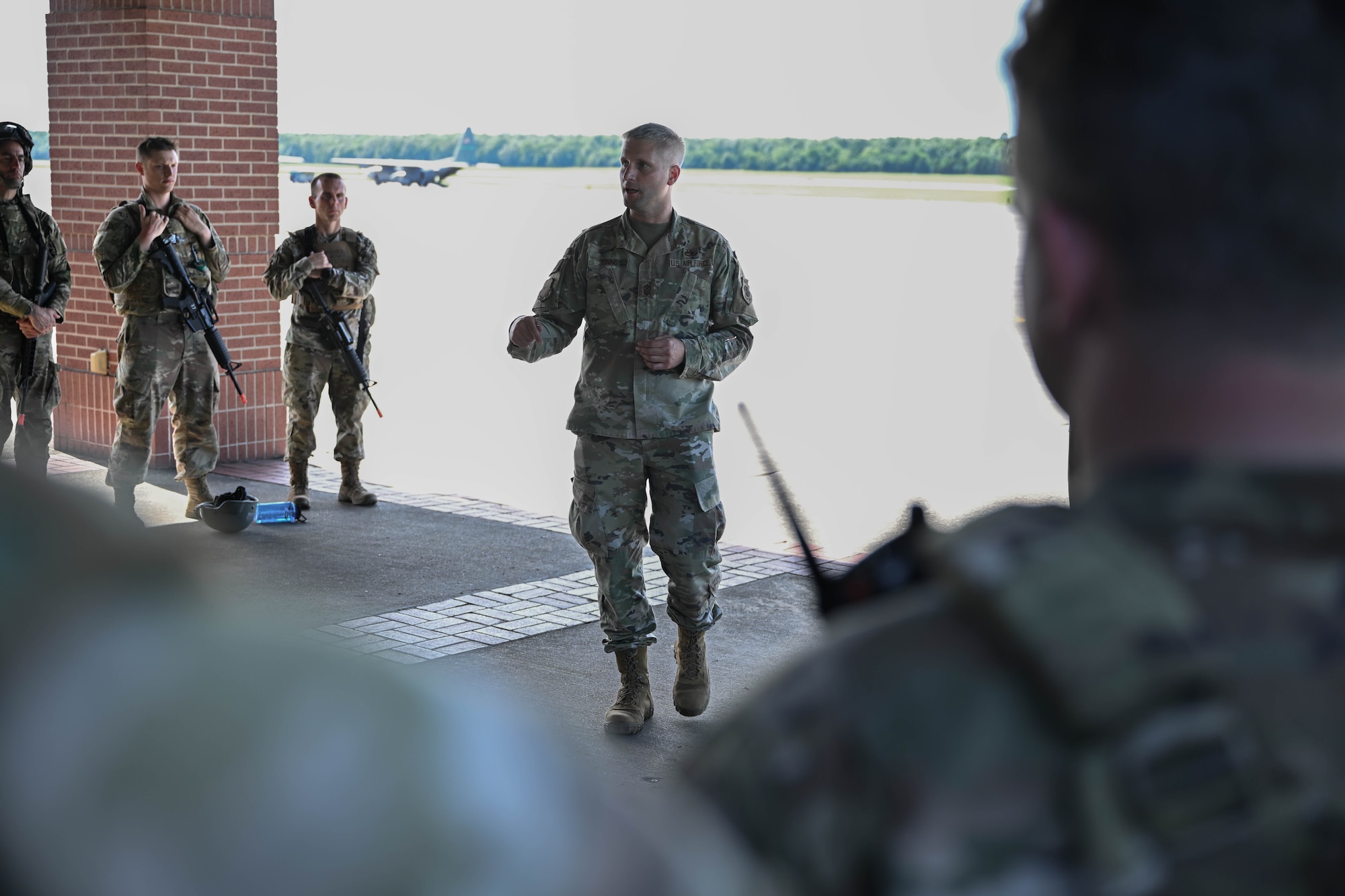 A man in uniform speaks to a group of people in uniform.