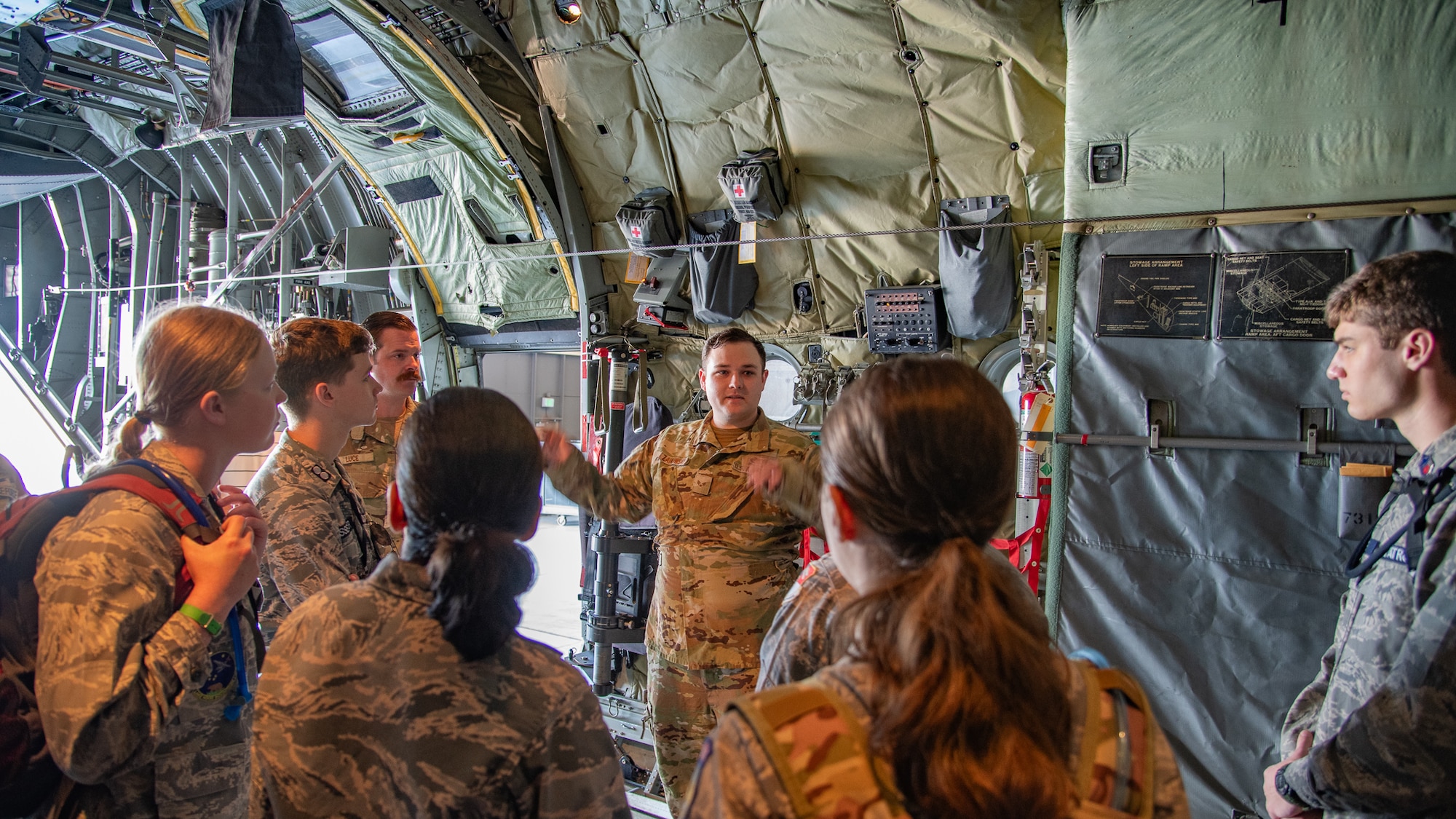 A group of people in military uniform stand in the cargo bay of an aircraft.