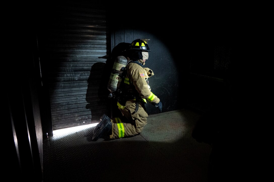 A photo of a blindfolded firefighter in a dark structural course.