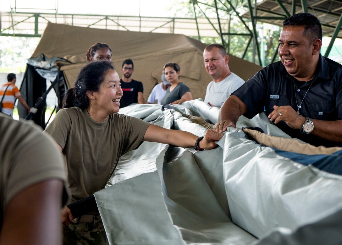 A photo of a female helping people hold a tent.