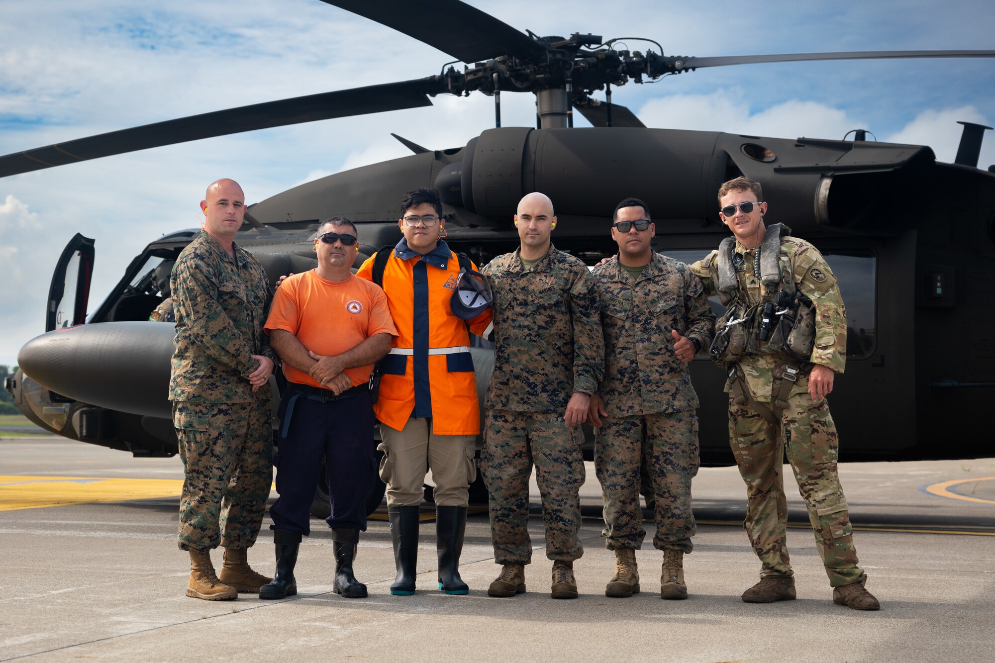 A photo of people posing in front of a helicopter.