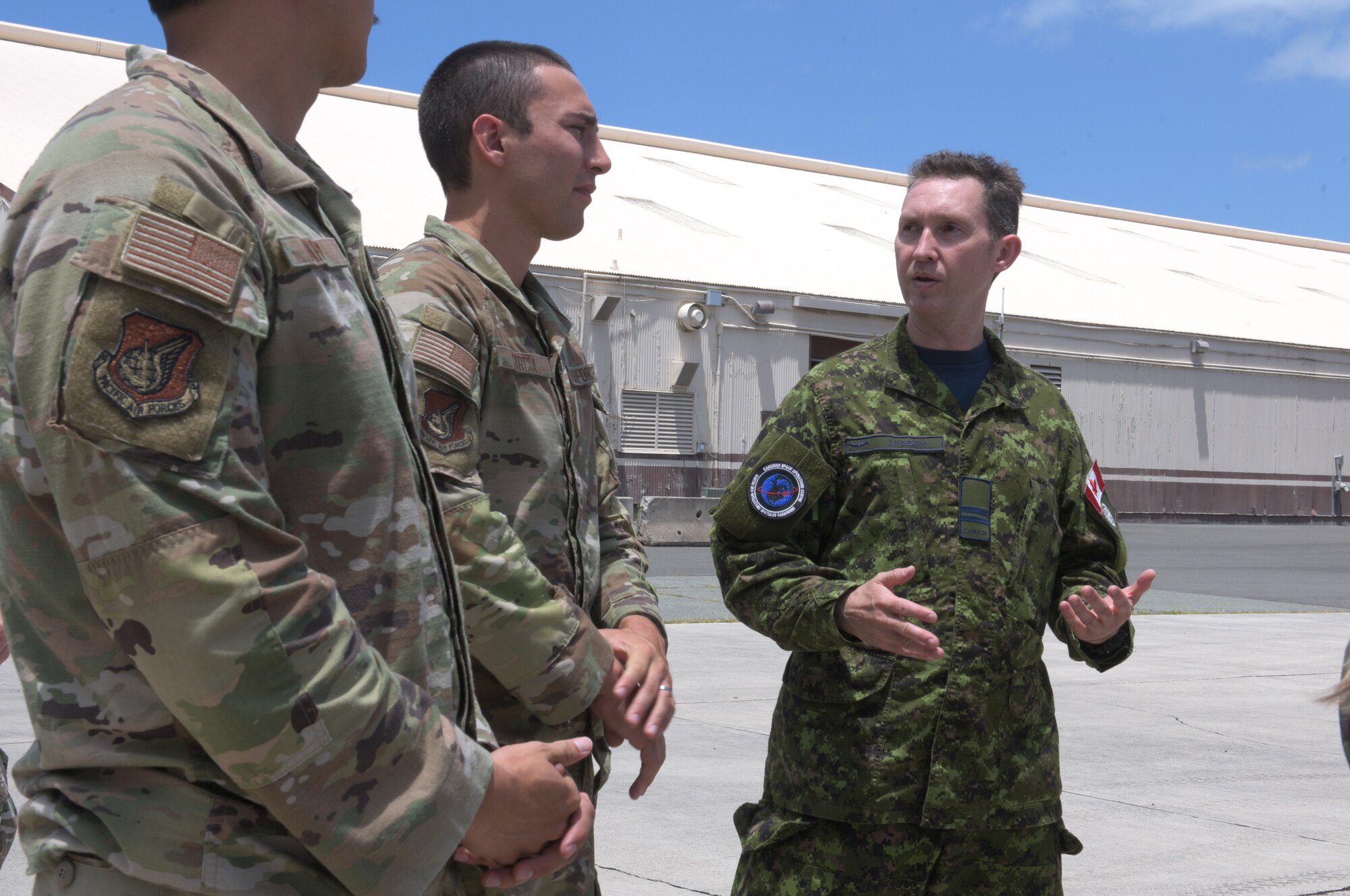 A Canadian Armed Forces member of the Royal Canadian Air Force’s 3 Canadian Space Division 7 Wing (Space) talks with U.S. Airmen as they work together with allies, partners and five U.S. service branches on the multinational space operations team in support of Valiant Shield 2024 (VS24), June 10, 2024, at Joint Base Pearl Harbor-Hickam, Hawaii. Throughout Exercise VS24, U.S. Space Command will plan, execute, and integrate military space power into multi-domain operations. Exercises such as VS24 provide Indo-Pacific Command Joint Forces an opportunity to integrate with allies and partners to conduct precise, multi-axis, multi-domain effects that demonstrate the strength and versatility of the Joint Force. (U.S. Air Force photo by Tech. Sgt. John Linzmeier)