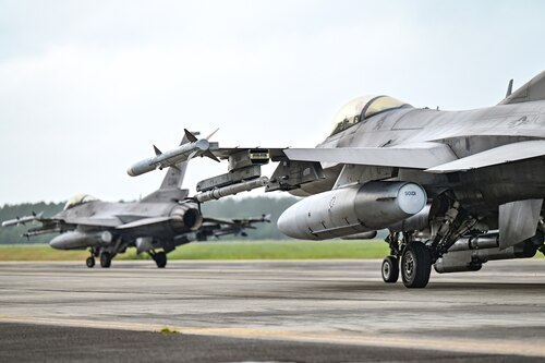 Two jets taxi across the flightline.