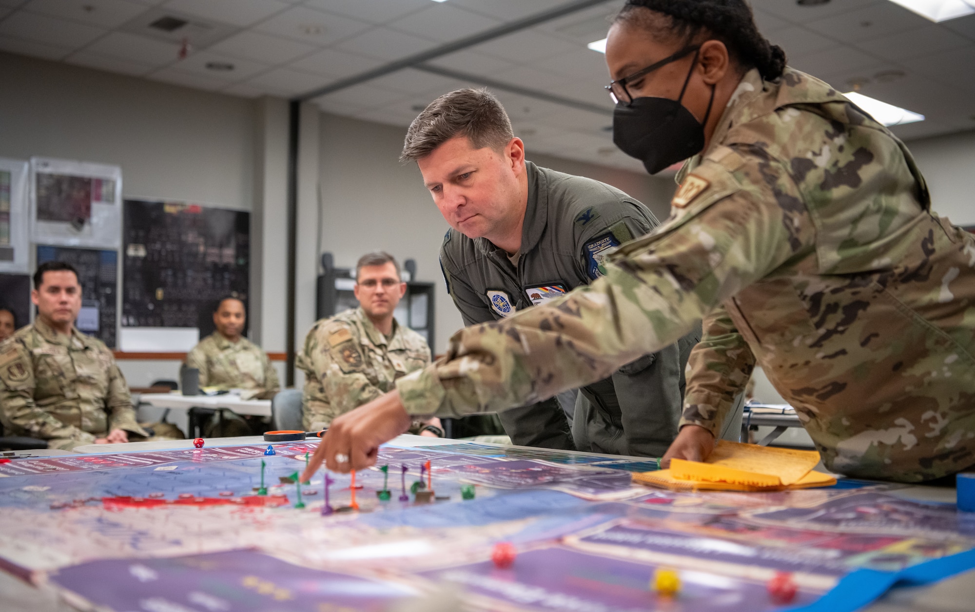 photo of uniformed U.S. Air Force major points to a point on a board game map while explaining to leadership what was learned during a Lead Wing Command and Control Course.
